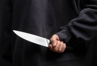 Arkasına bıçak saklayan bir suçlu, elinde silah tutan bir adam. Yakın çekim, silahlı saldırı konsepti..