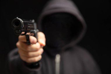 Siyah kapüşonlu silahlı soyguncu ateş etmeye hazır. Silahlı gangster suçlu, katil. Silah, şiddet kavramı