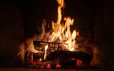 Şöminede yanan ateş, odun kütükleri ve parlak alevler. Sıcak bir ev, sıcak. Noel tatili