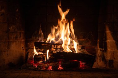 Şöminede yanan ateş, odun kütükleri ve parlak alevler. Sıcak bir ev, sıcak. Noel tatili