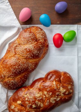 Paskalya tatlı ekmeği, iki tsoureki örgü ve masanın üstünde renkli Paskalya yumurtaları.