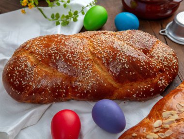 Paskalya tatlı ekmeği, iki tsoureki örgü ve masanın üstünde renkli Paskalya yumurtaları.