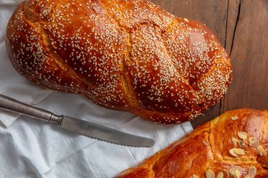 Easter sweet bread, two tsoureki braids and knife on a white cloth on the table, top view clipart