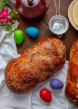 Paskalya tatlı ekmeği, iki tsoureki örgü ve masanın üstünde renkli Paskalya yumurtaları.