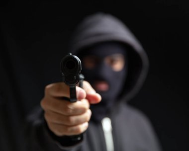 Kar maskeli silahlı bir suçlu, ateş etmeye hazır. Silahlı kapüşonlu katil silahı, suç şiddeti kavramı