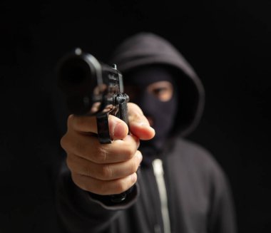Elinde kar maskesi olan bir soyguncu ateş etmeye hazır. Silahlı kapüşonlu katil silahı, suç konsepti