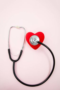 Tıbbi steteskop ve kırmızı kalp pastel pembeye izole edilmiş. Dünya Sağlık Günü, Aşk Konsepti