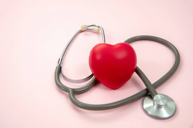 Tıbbi steteskop ve kırmızı kalp pastel pembeye izole edilmiş, yakın çekim. Dünya Sağlık Günü, Aşk Konsepti