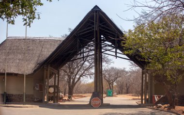 Kruger Ulusal Parkı, giriş kapısı kontrol. Güney Afrika. Tahta çatı, dur işareti ve güvenlik parmaklıkları.  