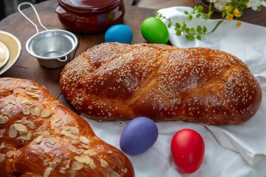 Paskalya tatlı ekmeği, iki tsoureki örgü ve masanın üstünde renkli Paskalya yumurtaları.
