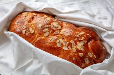 Paskalya tatlı ekmeği, beyaz masa örtüsü üzerinde ev yapımı tsoureki örgü, yakın çekim manzarası.