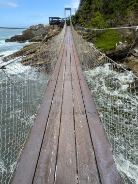 Tsitsikamma National Park, South Africa. Suspension Bridge over Storms River. cloudy blue sky clipart