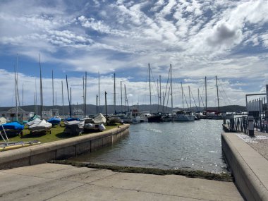 Knysna lagoon marina South Africa. Sailboats and yachts in the sea and on the grass, blue cloudy sky clipart