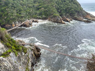 Tsitsikamma Ulusal Parkı, Güney Afrika. Fırtına Nehri üzerindeki asma köprü, dalgalı okyanus. Yukarıdan görüntüle