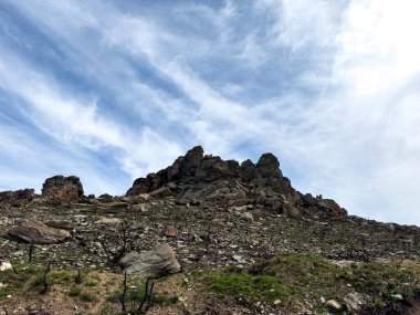 Atina yakınlarındaki Penteli dağının Rocky yamacı, bulutlu mavi gökyüzü. Vahşi ateş kalıntıları, kayalar ve yeşil çimenler