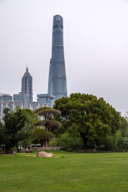Şangay şehrinin yüksek binaları bulutlu gökyüzüne, Çin 'e karşı. İş ve konut gökdelenleri ve şehir parkı