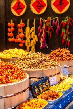 Çin Xitang 'ı. 30 Mart 2025. Çin market tezgahı, çeşitli karıştırılmış frid ve büyük ahşap kaselerde salamura yiyecekler..