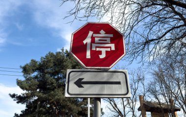 Çince işaret levhası ve sol tarafta ok işareti var. Çin 'deki arabalar için trafik işaretleri, mavi bulutlu gökyüzü ve ağaçlar.