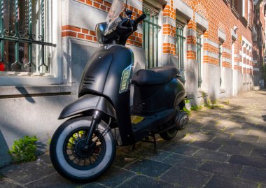 Hollanda 'da bir binanın önüne park edilmiş Scooter model bir motosiklet.
