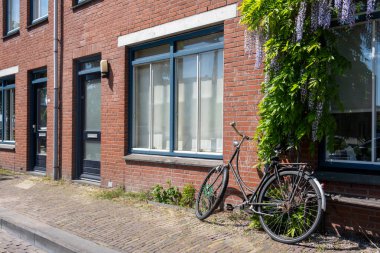 Delfshaven 'daki tuğla duvar binasının önündeki kaldırıma park edilmiş bisiklet. Hollanda 'da bisiklet sürmek