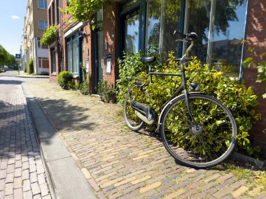 Delfshaven 'daki tuğla duvar binasının önündeki kaldırıma park edilmiş bisiklet. Hollanda 'da bisiklet sürmek