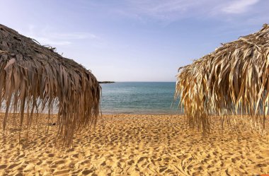 Kumsalda saman şemsiyeler, yakın çekim. Denizde güneşli bir gün. Yunanistan 'da yaz tatilleri