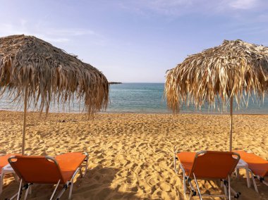 Saman şemsiyeler ve kumlu sahilde güneşli bir gün. Yunanistan 'da yaz tatilleri