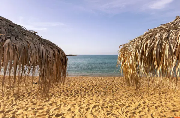 Kumsalda saman şemsiyeler, yakın çekim. Denizde güneşli bir gün. Yunanistan 'da yaz tatilleri