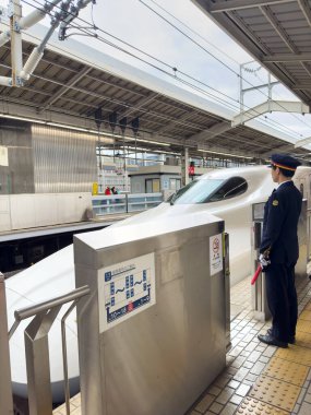 Japonya, Kyoto. 9 Nisan 2024, Shinkansen mermi treni Japon demiryolu platformunda durmakta olan bir istasyon görevlisiyle