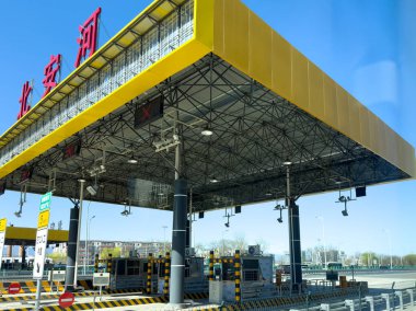 Pekin, Çin, 24 Mart 2025. Otoyolda sarı çatılı bir tren istasyonu, bir sürü güvenlik kamerası ve trafik levhası, mavi gökyüzü..