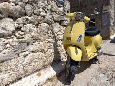 Sarı moto Mesta ortaçağ köyünde dar bir sokağa park edilmiş. Chios Adası, Yunanistan. Geleneksel mimari taş evler
