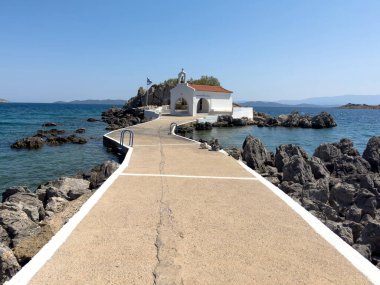 Agios Isidoros küçük kilise, Chios Adası, Yunanistan. Dar beton bir geçitle kıyıya bağlı kayalık bir adada geleneksel mimari şapel.