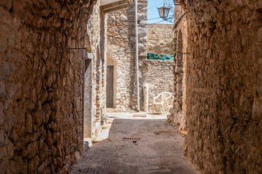 Chios Adası, Yunanistan. Mesta Ortaçağ köyündeki dar kaldırım taşı sokağı. Geleneksel mimari taş evler ve kemerler. Kırsal ahşap kapılar ve fener.