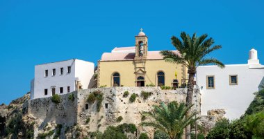 Yunanistan 'ın Girit adasındaki kayalık tepedeki Krisoskalitissa Manastırı. 17. yüzyıl Doğu Ortodoks Hıristiyan Manastırı. Taş duvarlar, palmiye ağaçları ve berrak mavi gökyüzü