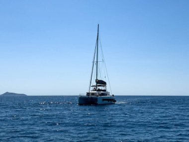Peloponnese kıyısındaki sakin mavi sularda seyreden katamaran açık yaz gökyüzü altında parlak gün ışığı altında