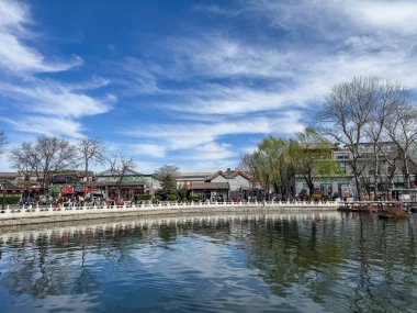 Pekin, Çin. 25 Mart 2025. Shichahai 'de göl kenarında yürüyen turistler, geleneksel Çin mimari binaları, mavi gökyüzü..