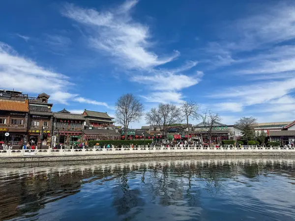 Pekin, Çin. 25 Mart 2025. Shichahai 'de göl kenarında yürüyen turistler, geleneksel Çin mimari binaları, mavi gökyüzü..