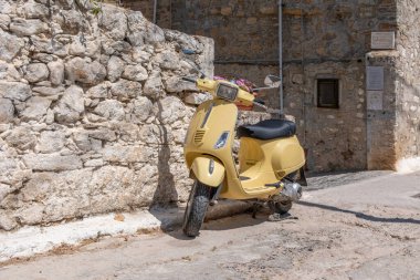 Sarı moto Mesta ortaçağ köyünde dar bir sokağa park edilmiş. Chios Adası, Yunanistan. Geleneksel mimari taş evler