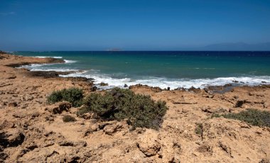 Gavdos Adası, Yunanistan. Tripiti Sahili. Kayalık sahil şeridi seyrek bitki örtüsü ve okyanus dalgaları mavi gökyüzü, yaz güneşli günü