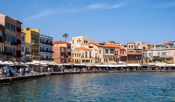 Hanya, Yunanistan, 21 Mayıs 2025. Rıhtımdaki eski Venedik liman binaları, kafelerin ve dükkanların etrafında gezinen insanlar, sakin deniz, mavi gökyüzü