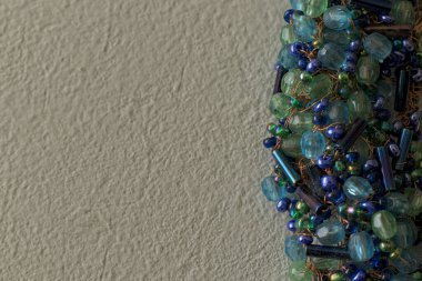 Beyaz bir yüzeye dokunmuş mavi ve yeşil boncuklu broşun yakın çekim görüntüsü