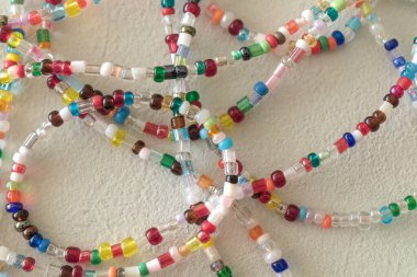 Beyaz bir yüzey üzerinde çok renkli boncukları olan bir kolyenin yakın çekim görüntüsü.