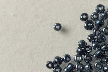 Nakış işlemek için gri cam boncuklar ve beyaz bir yüzeye takılar.