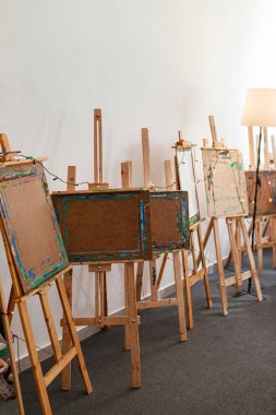 Resim stüdyosunda üzerinde boya lekeleri olan tahta sehpalar. Doğal ışıklandırmalı yaratıcı uzay düzeni. Sanat, yaratıcılık, eğitim veya atölye çevresindeki temalar için ideal.