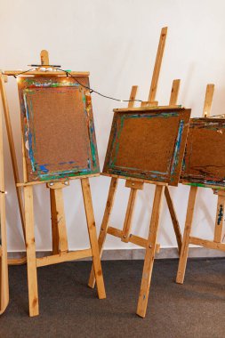 Yayın ışıklarıyla çerçevelenmiş, ağır kullanımla sanat sehpalarının yatay görünümü. Bir panelde iç mekan çizimi var. Yaratıcı ya da sanat temalı editör içeriği için mükemmel.