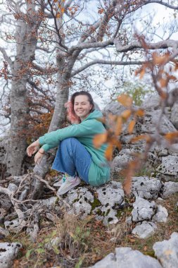 Çift, sonbahar yollarında dağdaki sislere bakıyor. Kol kola duran çift, sisli orman patikalarına, altın yapraklara, sise ve kayalık kenarlara bakıyor. Açık havada sakin bir atmosfer yaratıyor..