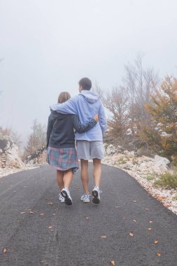 Sonbahar ağaçları ve beyaz taş arazilerle çevrili, sisli dağ boyunca kıvrımlı yol boyunca uzanan kavisli yola bakarken hatunları kucaklıyor..