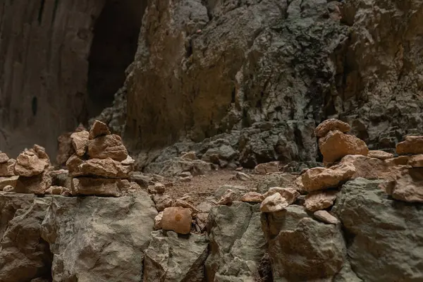 Mağaradaki istiflenmiş kaya mağaralarının yakın görüntüsü, engebeli taş yüzeyde dinleniyor. düzinelerce küçük taş yığını desenli yeşil-gri kayaların üzerinde duruyor. Dikkatlice dengelenmiş kayalar mağara zeminine karşı sembolik şekiller yaratır..