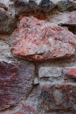 Yıpranmış antik duvarlara gömülü büyük ve canlı bir mineral taş. Geleneksel Akdeniz binası tekniğini vurgulayan eski, pürüzsüz taş duvar yapısı içindeki parlak çok renkli mineral kayanın detaylı görüntüsü..