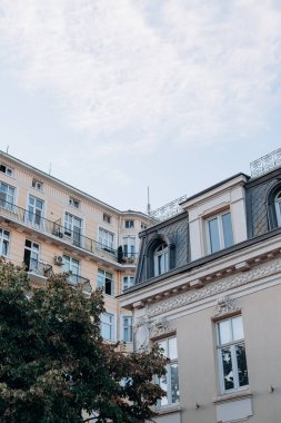 Sofya. Bulgaristan. 09.19.2025. Büyük camları, metal balkon korkulukları, pastel sarı cepheli, güpegündüz yakalanmış Avrupa mimarisi..